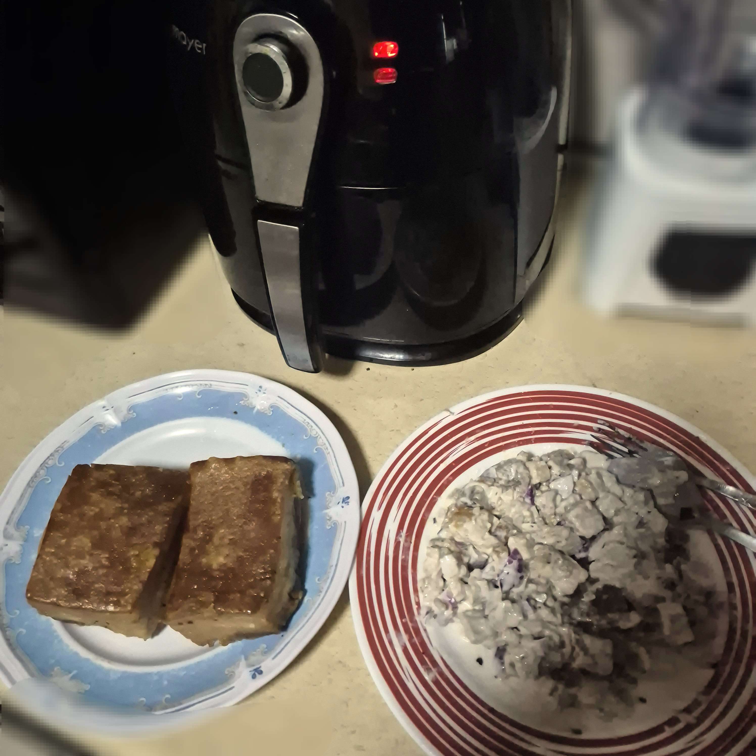 Picture of a plate of sisig and a plate of lechon kawali beside an air fryer